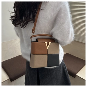 Detail of color-block leather bag with golden V-buckle and pebble texture finish