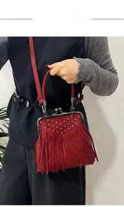 Detail of red suede crossbody bag with fringe tassels, silver studs and kiss-lock frame