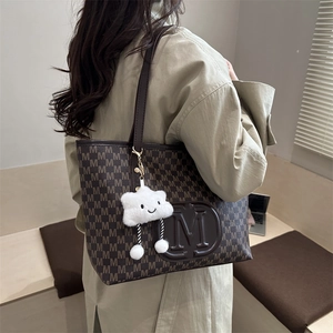 Detailed view of brown PU tote bag featuring M monogram and white plush cloud charm
