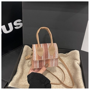 Detailed macro of a mini color-block straw woven crossbody bag held in hand