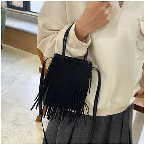 Detail of black bohemian tassel bag with suede texture and adjustable shoulder strap