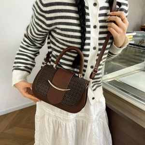 Detail of dark brown leather handbag with woven side texture and golden crescent buckle