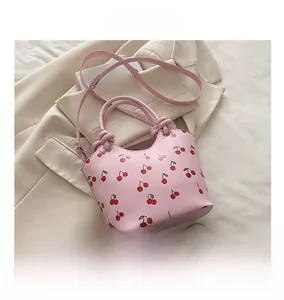 Detail of pink cherry print tote bag with dual handles and metal eyelets on beige fabric