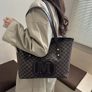 Close-up of the vintage PU tote bag with repeated M pattern and gold rivet accents