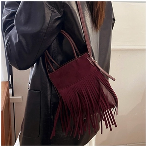 Detailed view of burgundy suede bucket bag with long tassels and gold metal buckle lock