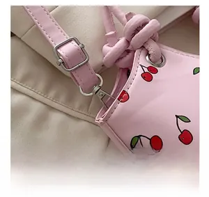 Detail of silver adjustable buckle and cherry print on pink faux leather shoulder bag