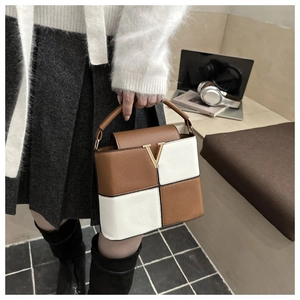 Detail of a brown and cream leather handbag with gold V logo in a city lifestyle setting