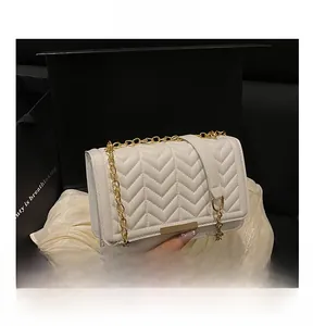 Gros plan du sac matelassé en V blanc avec chaîne dorée dans un coffret cadeau