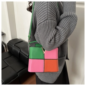 Detail of color-block crossbody bag with lychee grain leather and golden V buckle