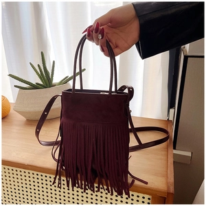 Close-up of bohemian burgundy bucket bag with vintage long fringe and matte leather texture