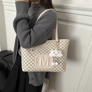 Close-up of cream PU leather tote bag with M pattern and fluffy cloud charm