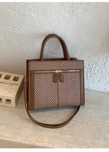 Details der braunen Vintage-Tasche mit Fischgrätenmuster und Doppelgriffen