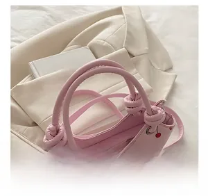 Pink handbag with cherry print featuring a unique twisted knot handle design