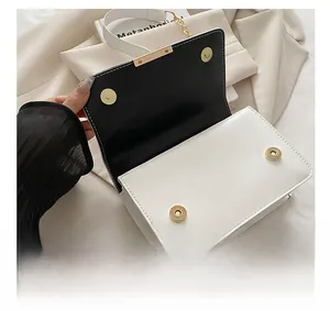 Détail de la fermeture magnétique et des ferrures dorées sur le sac noir et blanc