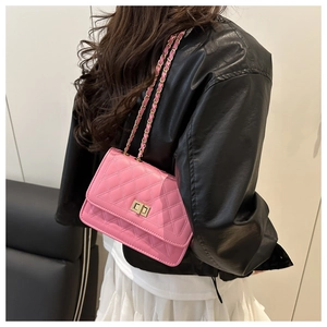 Detail shot of pink quilted chain bag with gold metal lock on a model outfit