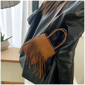 Close-up of vintage brown suede crossbody bag with long tassels and adjustable strap