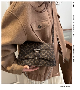 Gros plan d'un sac bandoulière marron caramel avec imprimé lettres et boucle argentée
