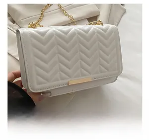 Détail du sac bandoulière blanc avec matelassage en V, chaîne dorée et fermoir