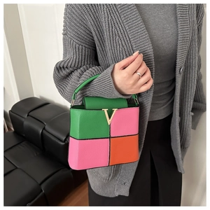 Detail of color-block leather handbag with golden V-clasp and pebbled texture