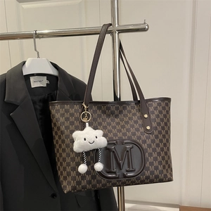 Detail of coffee brown PU tote bag with M-letter prints and cloud plush charm