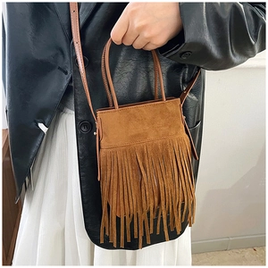 Close-up of brown suede tassel bucket bag with bohemian fringe detail and leather strap