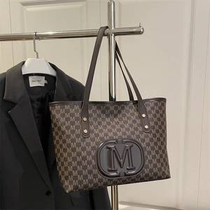 Detail view of the brown M-letter monogram print and faux leather tote bag handle