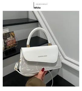 Detailaufnahme der weißen Handtasche aus Leder mit Mode-Schriftzug und Goldschnalle