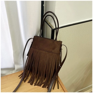 Close-up of brown suede bucket bag featuring bohemian tassels and gold zipper detail