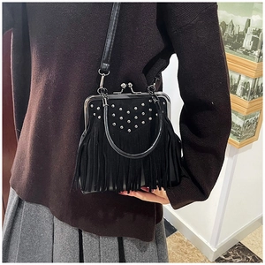 Detail of black suede handbag featuring silver metal rivets and long fringe tassels