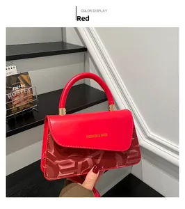 Detailansicht der roten strukturierten Lederhandtasche mit goldenen Beschlägen und Schrift