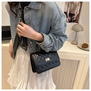 Detail of a black quilted crossbody bag with a gold metal twist lock and chain strap