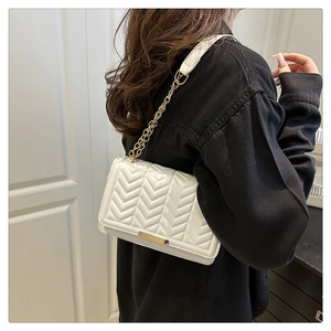 Gros plan du sac bandoulière blanc matelassé avec chaîne dorée et finitions métalliques