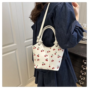 Detail of white cherry print tote bag with adjustable shoulder strap and metal hardware