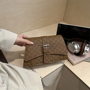 Sac bandoulière monogramme marron avec chaîne argentée et boucle dans un décor lifestyle