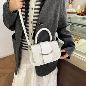 White croc-effect crossbody handbag with gold buckle shown on a model in a cafe setting