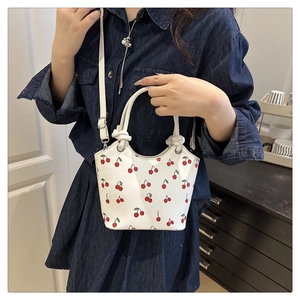 Detail of white cherry print bucket bag with knotted handle and adjustable strap