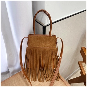Detail of bohemian brown suede bucket bag featuring dense fringe tassels and long strap