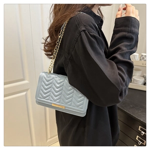 Détail du sac matelassé bleu clair avec bandoulière chaîne dorée et décorations