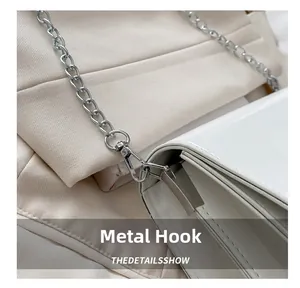 Détail de la chaîne argentée et du fermoir sur le sac bandoulière en cuir verni blanc