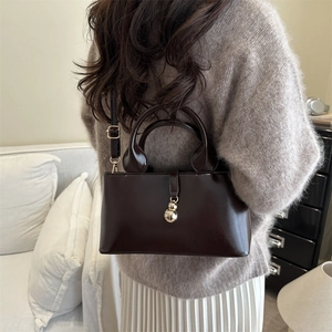 Deep brown glossy PU leather tote bag details with gold bead charms and a slim strap