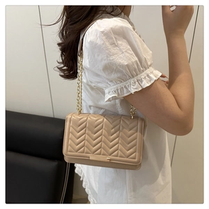 Détail du sac matelassé beige avec chaîne dorée et fermoir métallique élégant