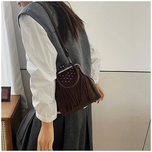 Detail of dark brown suede shoulder bag with bohemian tassels and silver metal rivets