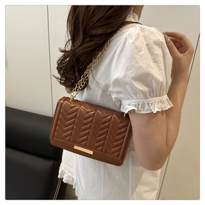 Vue détaillée du sac en cuir marron à surpiqûres en V avec chaîne dorée à l'épaule