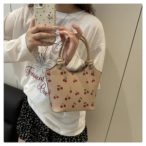 Mirror selfie showing a beige tote bag with red cherry prints and round handles