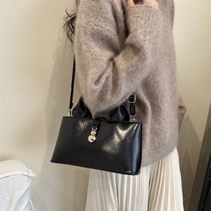 Detail of black patent leather tote bag with gold ball clasp and knotted handle