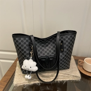 Detail of black tote bag with M-pattern texture and white cloud plush charm accessory