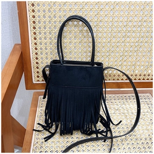 Close-up of black bohemian suede bucket bag with long tassels on a vintage wooden chair