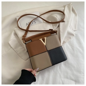 Macro detail of color-block tote bag with pebble leather texture and golden V hardware