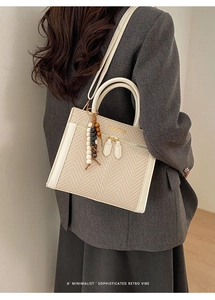 Detail der beige gewebten Handtasche mit Perlenquaste und Goldverzierung am Schultergurt