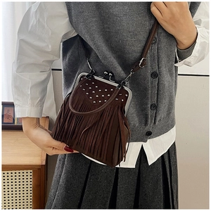 Close-up of vintage brown fringe crossbody bag with silver rivets and metal clasp